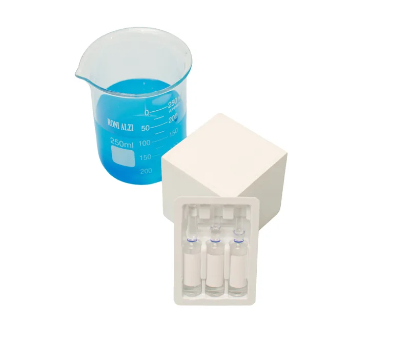 Béquer com líquido azul à frente de um berço plástico branco com cavidades para ampolas